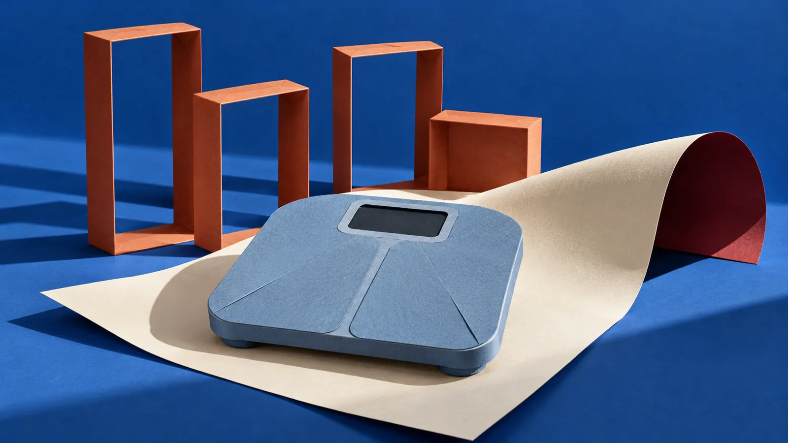 Sculptural blue paper bathroom scale with a blank display, four terracotta frames and a curled ivory sheet